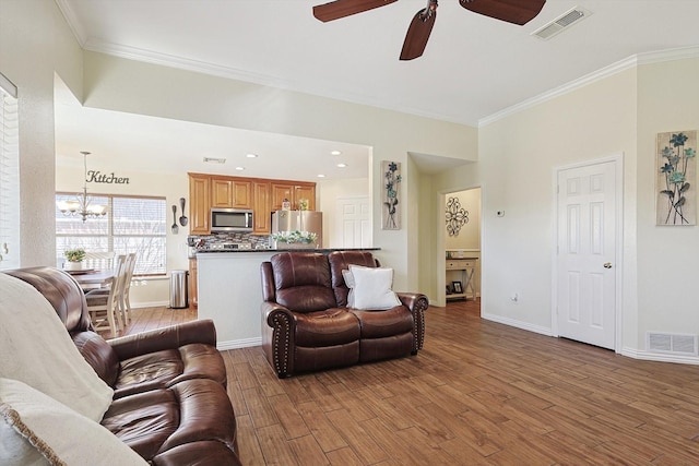 living room with ornamental molding, ceiling fan with notable chandelier, and hardwood / wood-style floors