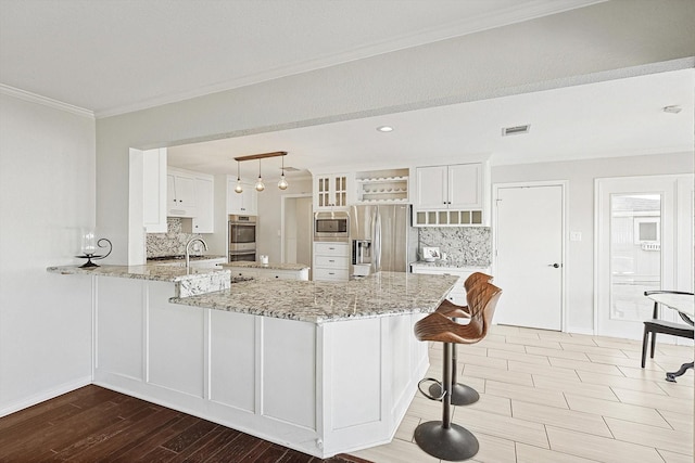 kitchen with visible vents, stainless steel appliances, a peninsula, a breakfast bar area, and crown molding