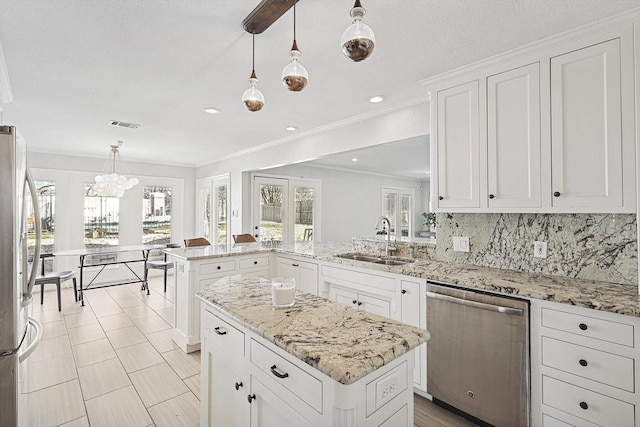 kitchen featuring backsplash, white cabinetry, a peninsula, stainless steel appliances, and a sink