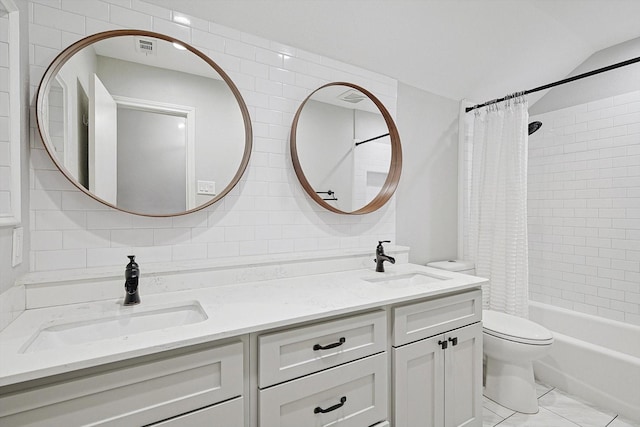 bathroom with a sink, backsplash, double vanity, and toilet