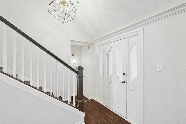 entryway featuring a chandelier, a textured ceiling, wood finished floors, and stairs