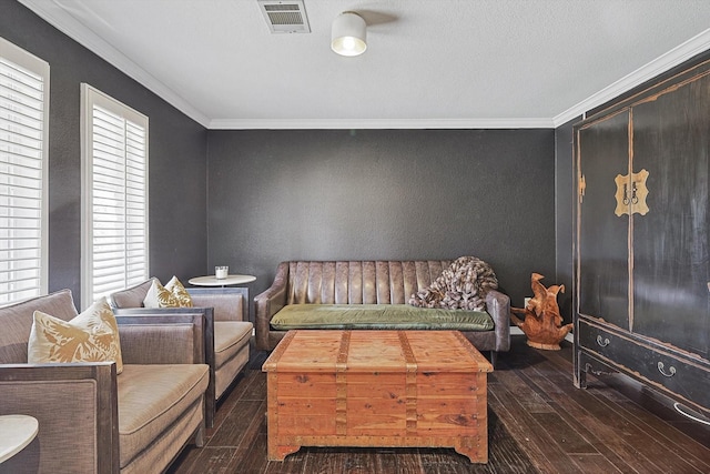 living area with hardwood / wood-style flooring, a textured wall, visible vents, and ornamental molding