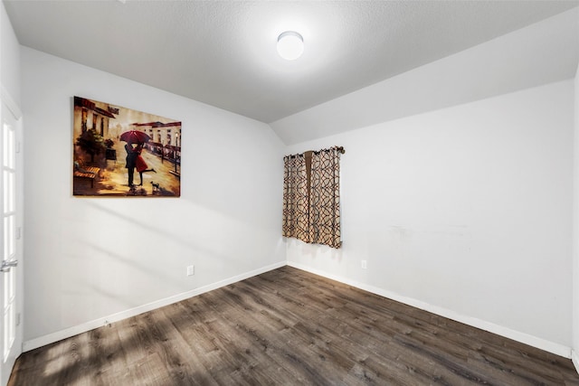 empty room featuring vaulted ceiling, dark wood-type flooring, and a textured ceiling