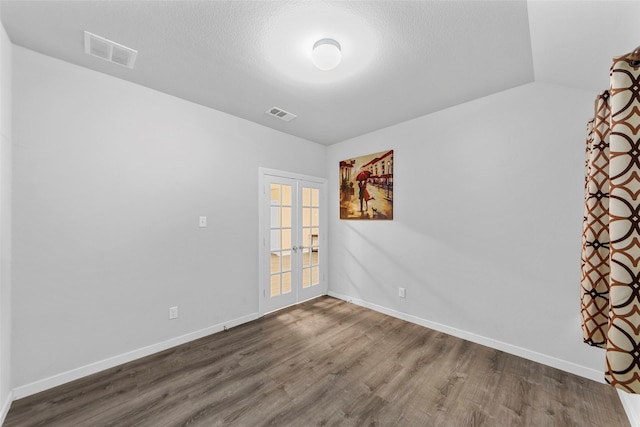 spare room featuring hardwood / wood-style floors, vaulted ceiling, and french doors