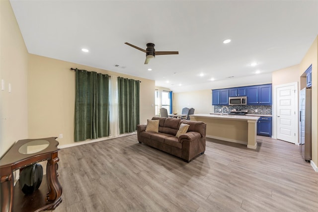 living room with ceiling fan, sink, and light wood-type flooring