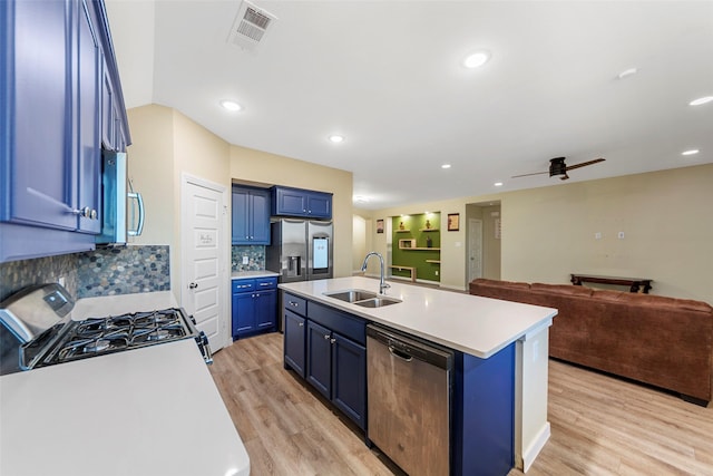 kitchen featuring sink, blue cabinetry, appliances with stainless steel finishes, a kitchen island with sink, and tasteful backsplash