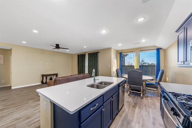 kitchen with sink, blue cabinetry, a kitchen island with sink, stainless steel appliances, and light hardwood / wood-style floors