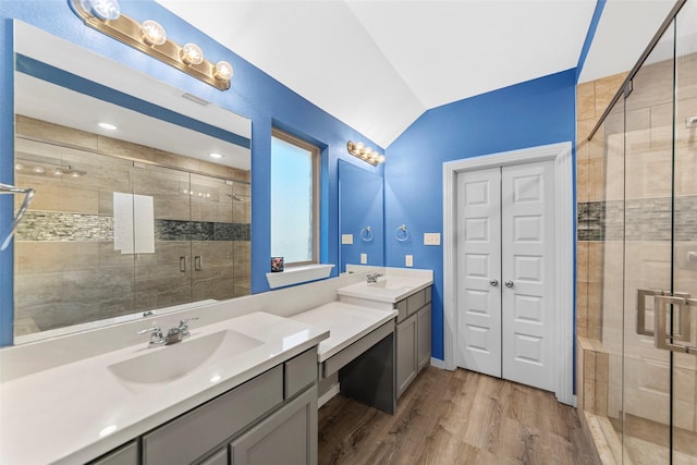 bathroom featuring hardwood / wood-style flooring, vanity, a shower with door, and vaulted ceiling