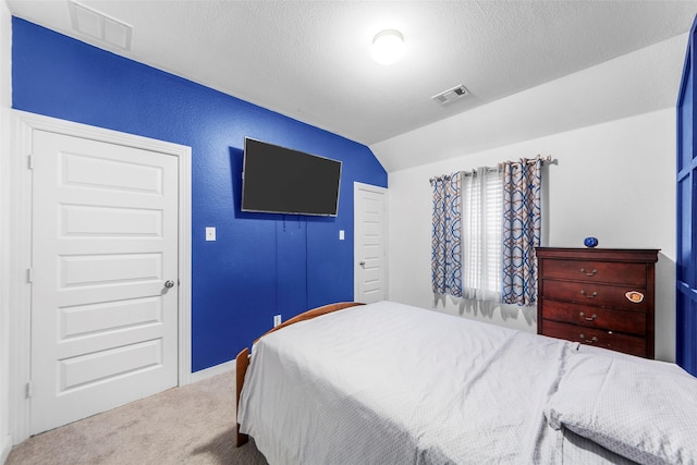 carpeted bedroom with vaulted ceiling and a textured ceiling