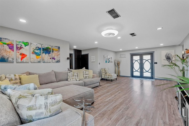 living area featuring light wood-style floors, recessed lighting, french doors, and visible vents