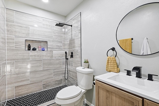 bathroom with vanity, a tile shower, and toilet