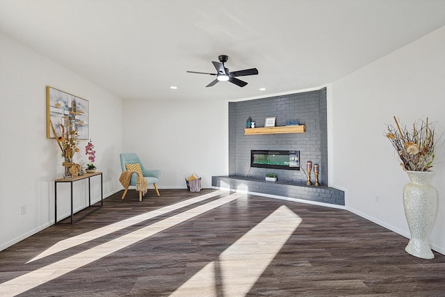 sitting room with dark hardwood / wood-style flooring, a brick fireplace, and ceiling fan