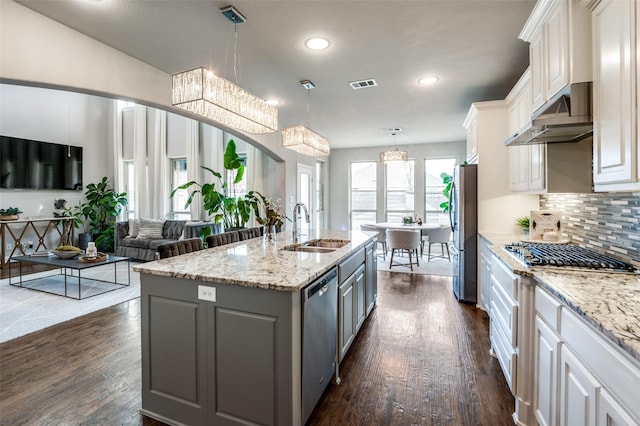 kitchen featuring sink, white cabinetry, hanging light fixtures, stainless steel appliances, and a kitchen island with sink