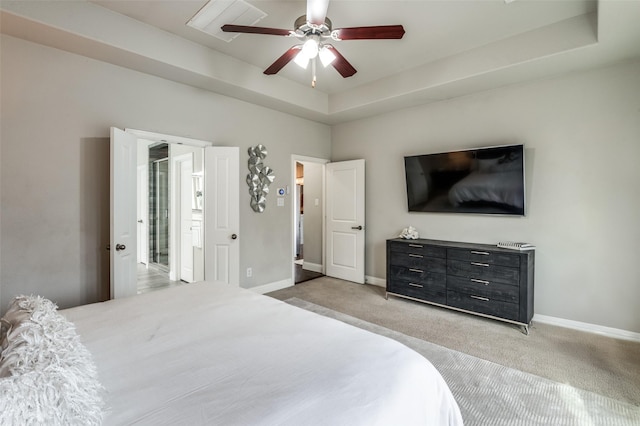 carpeted bedroom with ceiling fan and a tray ceiling