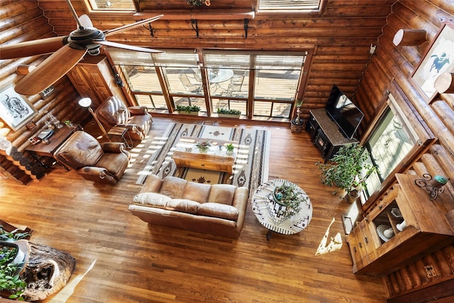 living room with log walls, a towering ceiling, and hardwood / wood-style flooring