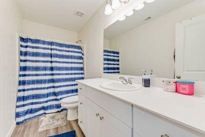 bathroom with vanity, toilet, curtained shower, and wood-type flooring