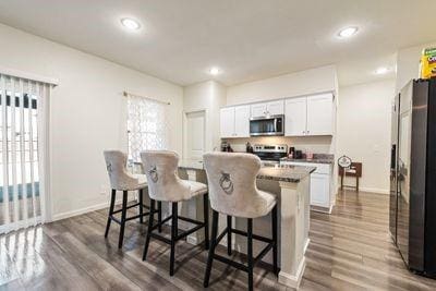 kitchen with white cabinetry, appliances with stainless steel finishes, a kitchen breakfast bar, and an island with sink