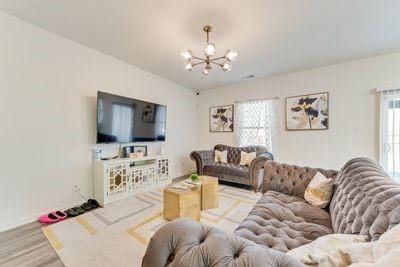 living room featuring wood-type flooring, plenty of natural light, and a notable chandelier