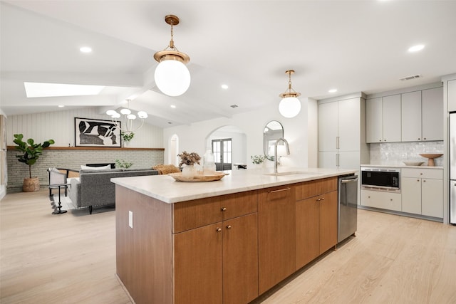 kitchen with a large island, lofted ceiling with skylight, sink, and white cabinets