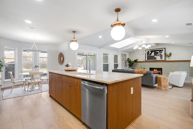 kitchen with sink, lofted ceiling with beams, light wood-type flooring, dishwasher, and a kitchen island with sink