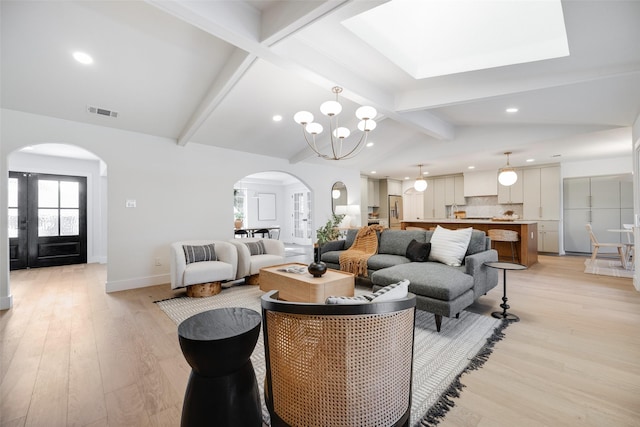 living room with lofted ceiling with beams, a notable chandelier, and light wood-type flooring