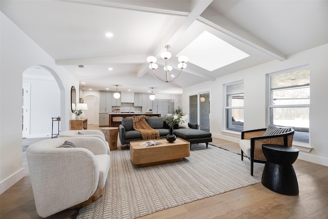 living room featuring a notable chandelier, wood-type flooring, and vaulted ceiling with beams