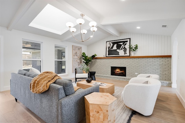 living room with a fireplace, a chandelier, lofted ceiling with beams, and light wood-type flooring