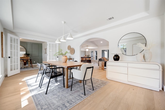 dining room with a tray ceiling, light hardwood / wood-style floors, and french doors