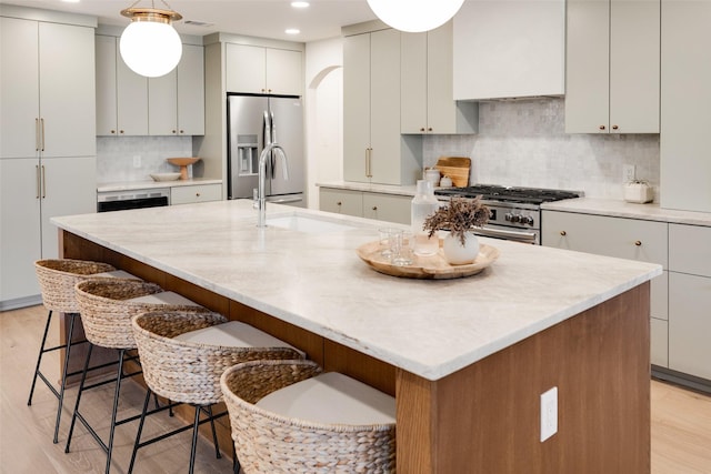 kitchen with a kitchen island with sink, a kitchen breakfast bar, and appliances with stainless steel finishes