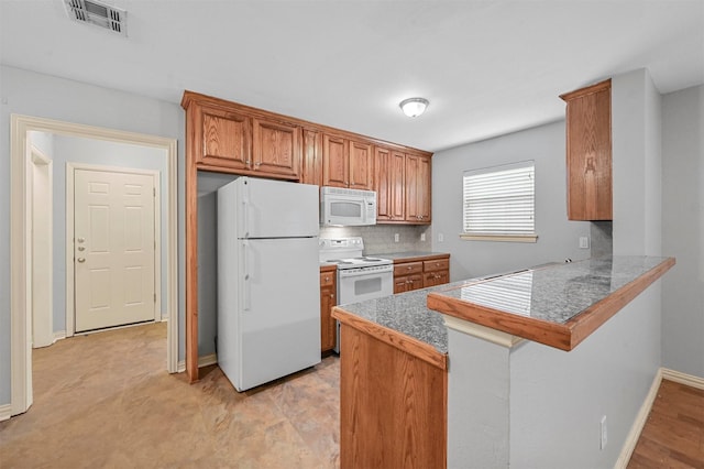 kitchen with tasteful backsplash, a breakfast bar area, white appliances, and kitchen peninsula