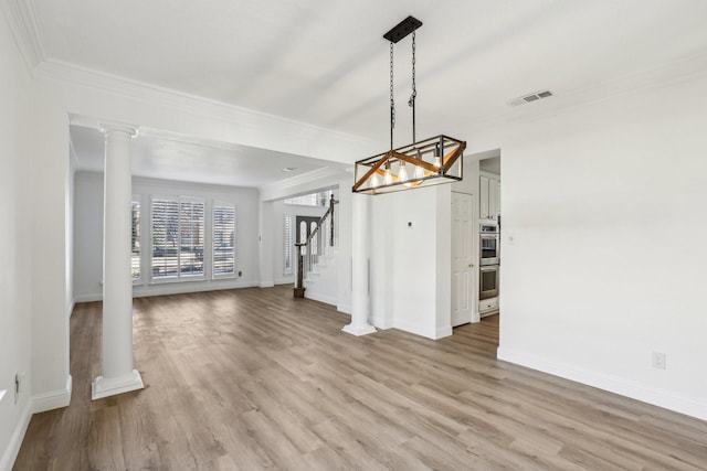 unfurnished dining area featuring crown molding, decorative columns, and light wood-type flooring