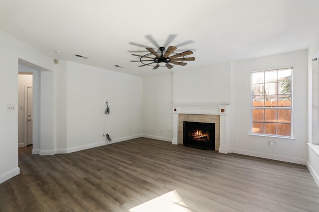 unfurnished living room with hardwood / wood-style flooring, a tile fireplace, and ceiling fan