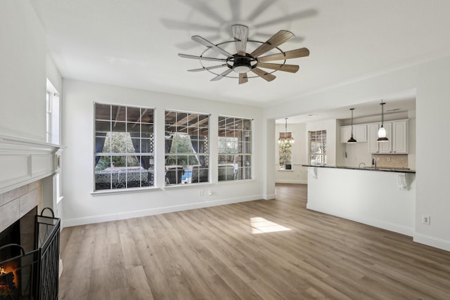 unfurnished living room with wood-type flooring, a fireplace, and ceiling fan