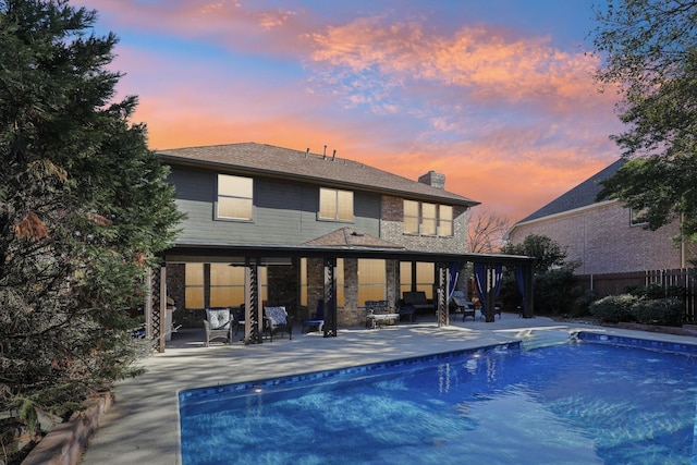 back house at dusk featuring a fenced in pool and a patio