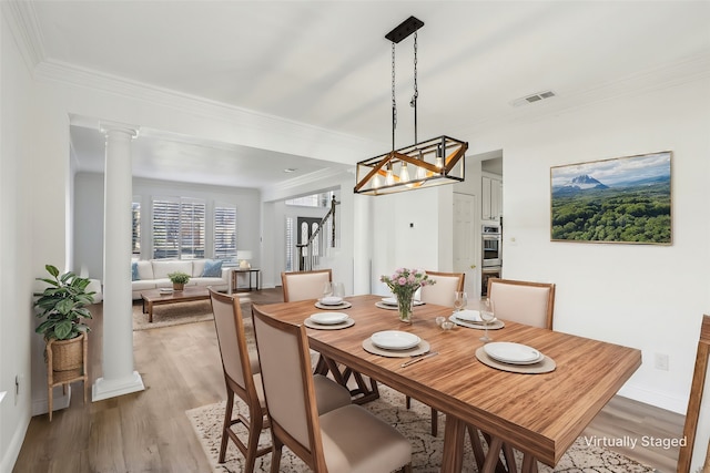 dining space featuring ornamental molding, decorative columns, and light hardwood / wood-style flooring