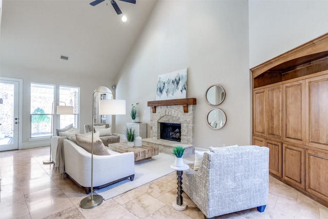 living room with ceiling fan, a stone fireplace, and high vaulted ceiling