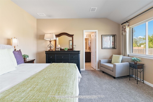 carpeted bedroom with ensuite bath and vaulted ceiling