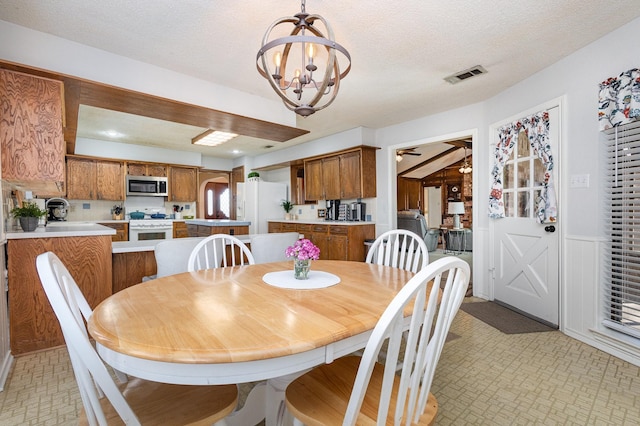 dining room featuring ceiling fan with notable chandelier and a textured ceiling