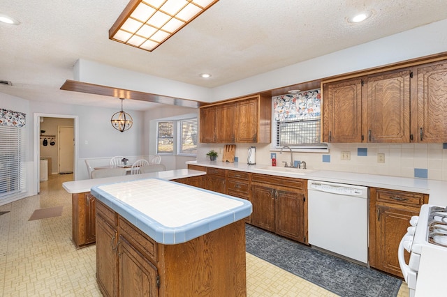 kitchen featuring sink, a textured ceiling, a kitchen island, pendant lighting, and white appliances