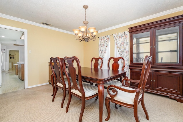 carpeted dining space featuring a textured ceiling, ornamental molding, and a chandelier