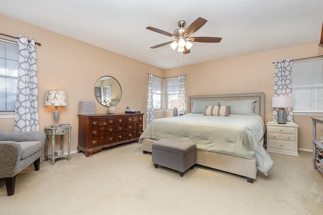 carpeted bedroom featuring ceiling fan and a textured ceiling