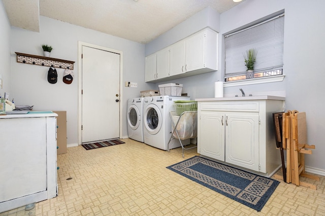 clothes washing area with independent washer and dryer, cabinets, and a textured ceiling