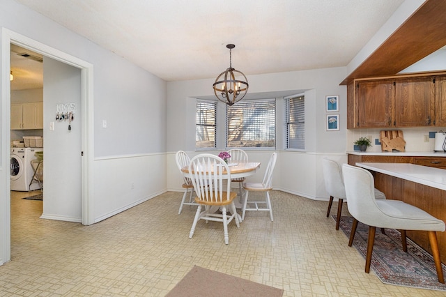 dining area featuring independent washer and dryer and a chandelier