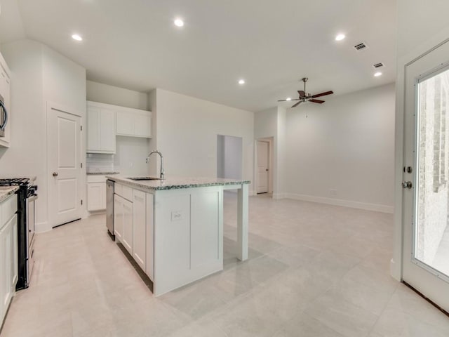 kitchen featuring dishwasher, white cabinetry, sink, a center island with sink, and black range