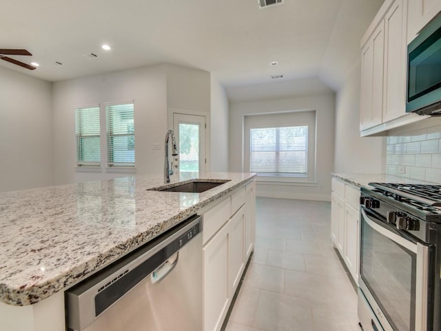 kitchen with sink, stainless steel appliances, tasteful backsplash, light stone countertops, and white cabinets