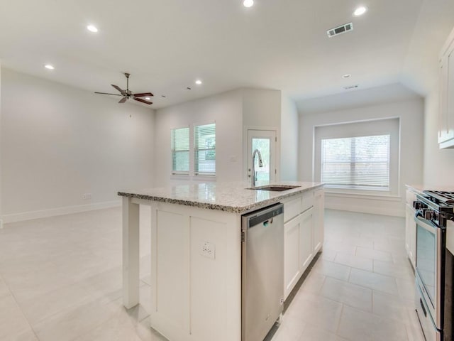 kitchen with sink, white cabinetry, light stone counters, appliances with stainless steel finishes, and an island with sink