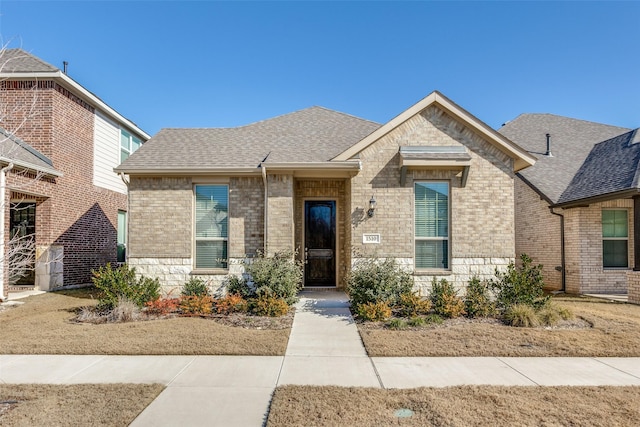 view of front of home featuring brick siding and a shingled roof