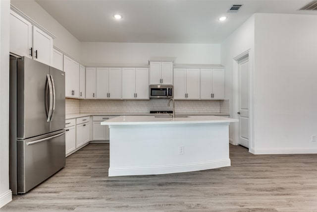 kitchen featuring sink, light wood-type flooring, stainless steel appliances, a kitchen island with sink, and white cabinets