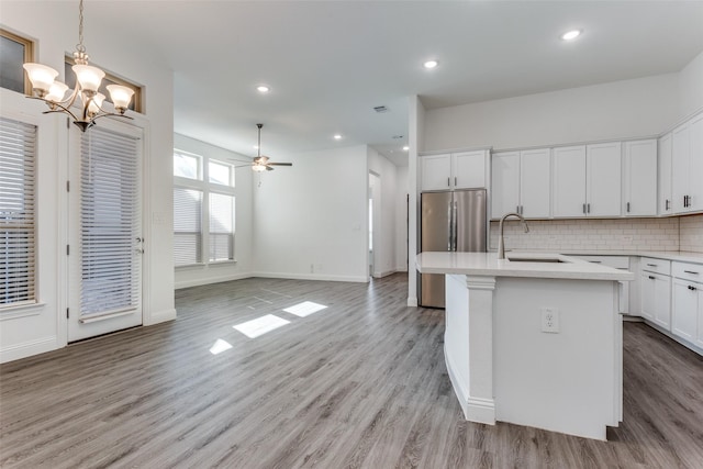 kitchen with white cabinets, sink, an island with sink, and backsplash