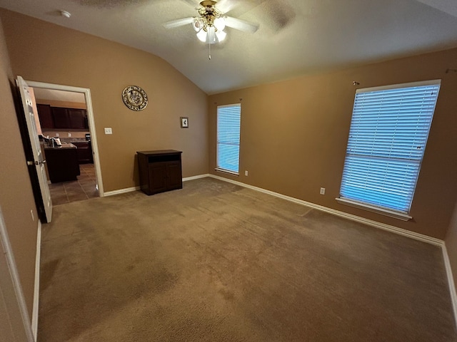 interior space with carpet floors, a textured ceiling, vaulted ceiling, and ceiling fan